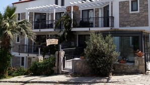 A two-story building with a white facade, stone accents, and a red-tiled roof. - Datça Zeytinevleri Apart (Datça)
