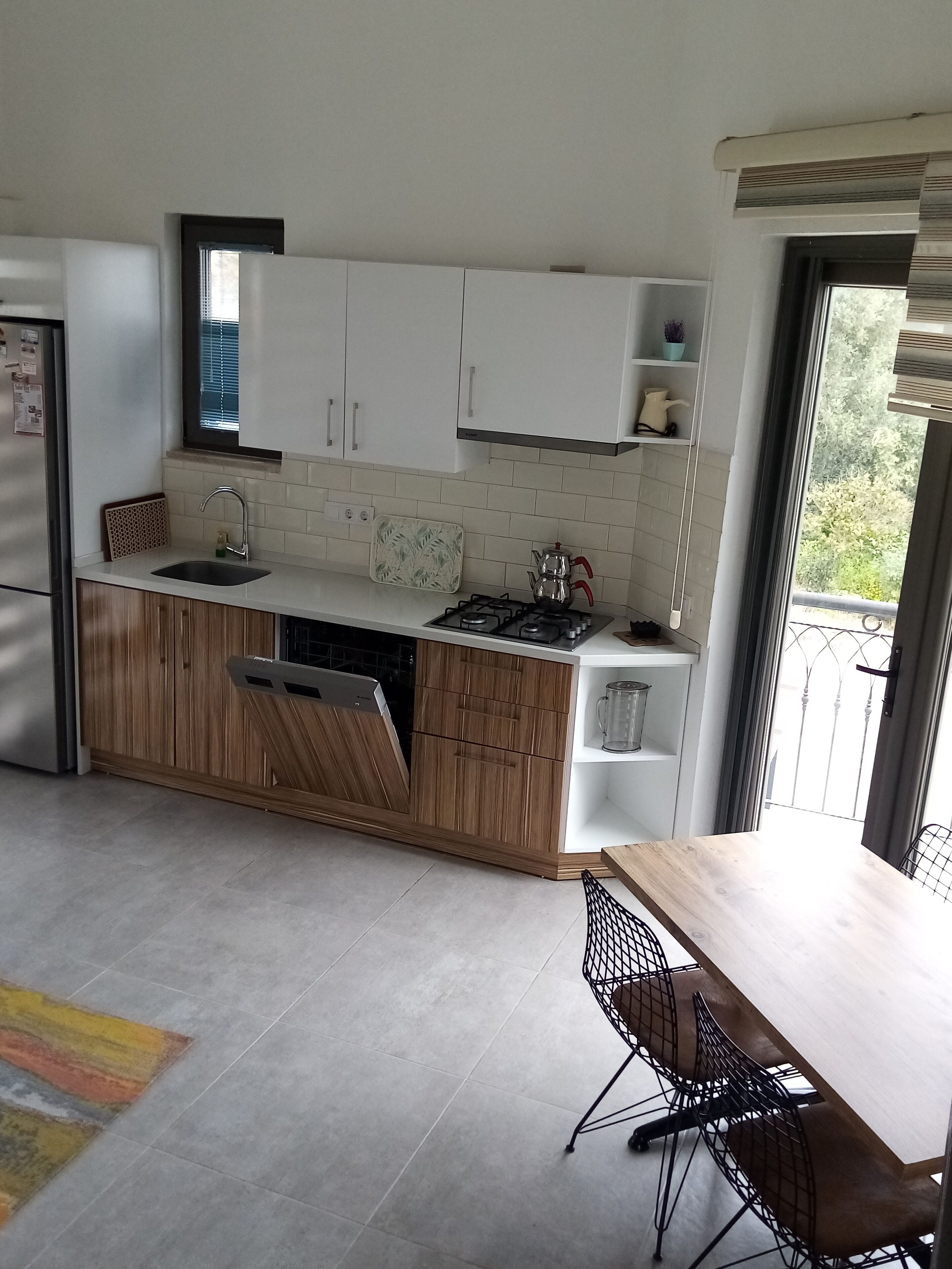 A modern kitchen with white cabinets, a gas stove, and a dining area with a table and chairs.