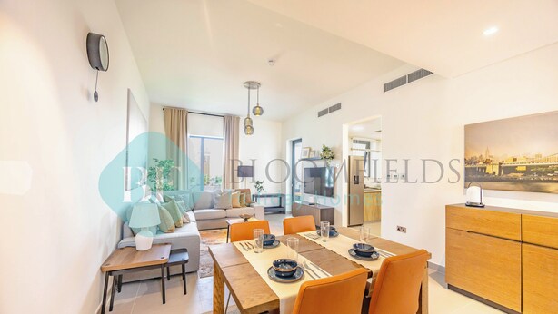 Una sala de estar moderna con sofá, mesa de centro y comedor con mesa dispuesta para cuatro.