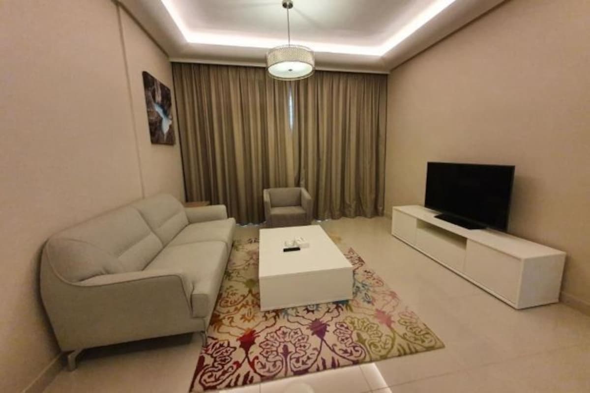 Una sala de estar moderna con un sofá, una mesa de centro, un televisor y una alfombra estampada.