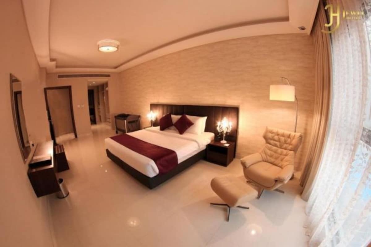 Una habitación de hotel moderna con una cama grande, una zona de estar y un escritorio independiente.