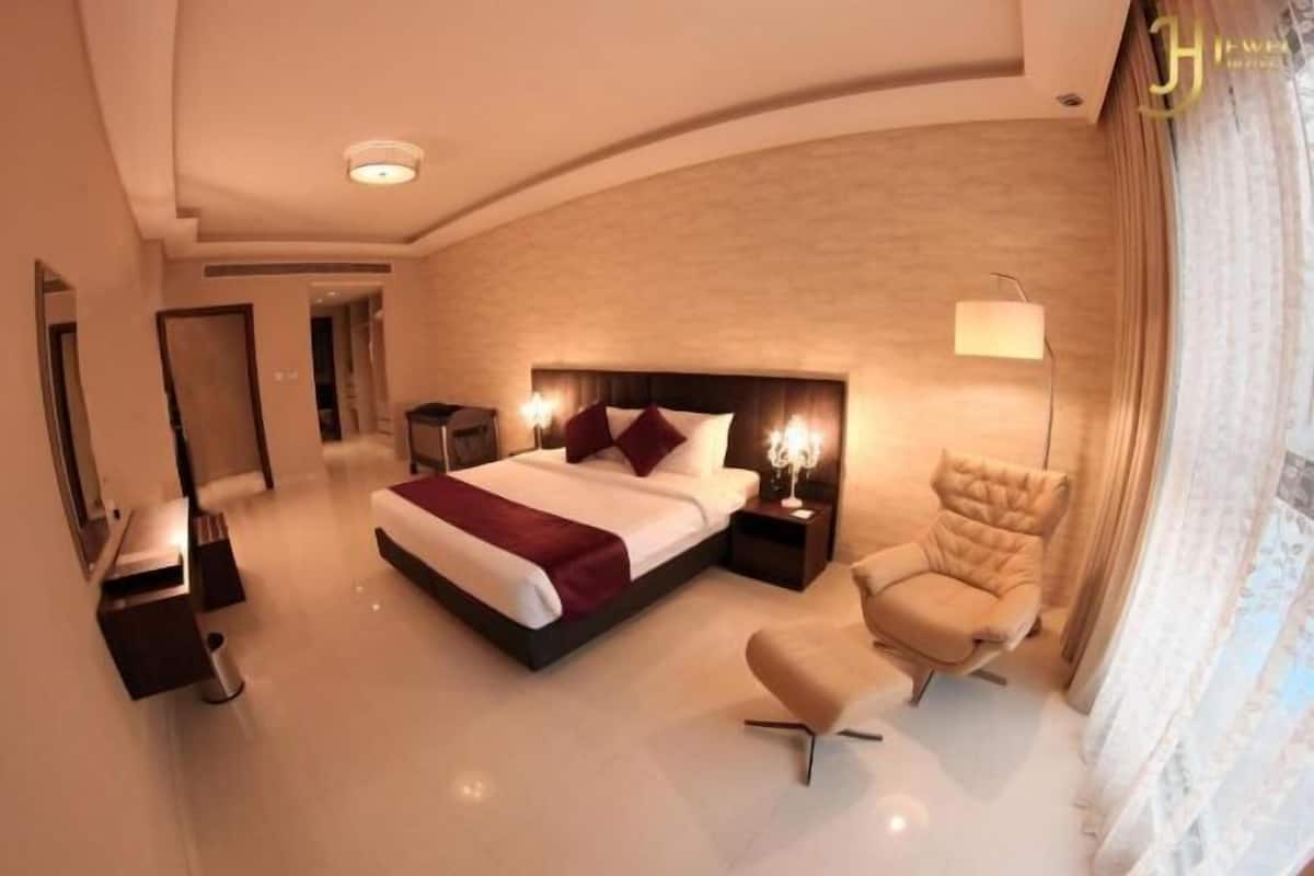 Une chambre d’hôtel moderne dotée d’un grand lit, d’un coin salon et d’un bureau séparé.