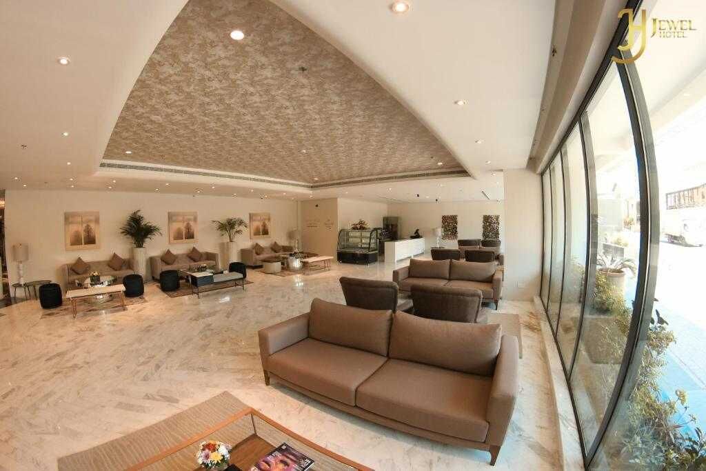 A spacious lobby with a high ceiling, a large seating area, and a view through large windows.