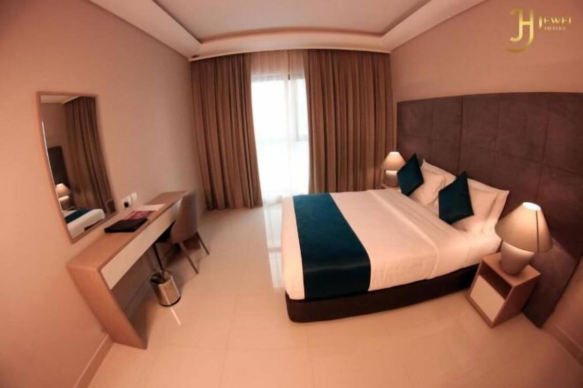 Une chambre d’hôtel moderne, dotée d’un grand lit, de tables de chevet, d’un bureau et d’un miroir.