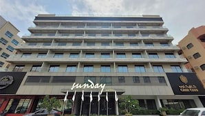 Een meerlaags hotel met een modern design, met een opvallend 'Sunday Hotel' bord bij de ingang.