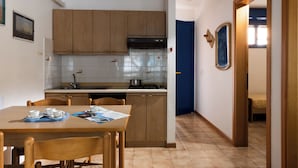 Een kleine keuken met houten kastjes, een gasfornuis en een betegelde spatwand.