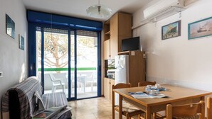 Een gezellige kamer met een bank, een eettafel met stoelen, een televisie en een koelkast.