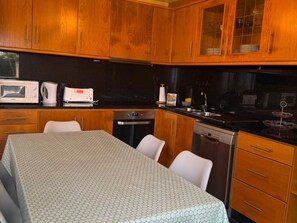 A kitchen with wooden cabinets, a microwave, a toaster, and a dining table with chairs.