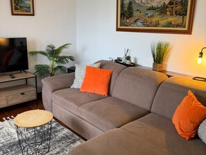 A living room with a sofa, a television, a coffee table, and a painting on the wall.