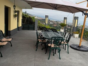 An outdoor patio with a table and chairs, a bench, and a view of a hillside town.