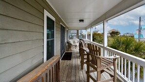 Eine überdachte Veranda mit Holzbalkonen und einer Reihe Adirondack-Stühle.