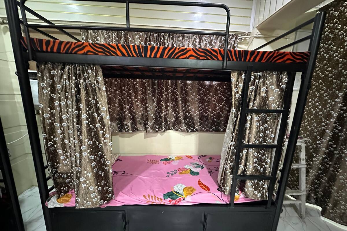 Uma cama beliche com corrimão listrado de zebra, cortinas florais e edredom rosa floral.