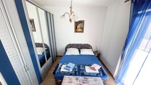 Ein Schlafzimmer mit einem Bett, einem Nachttisch, einem Spiegel und einem Fenster mit Vorhängen.