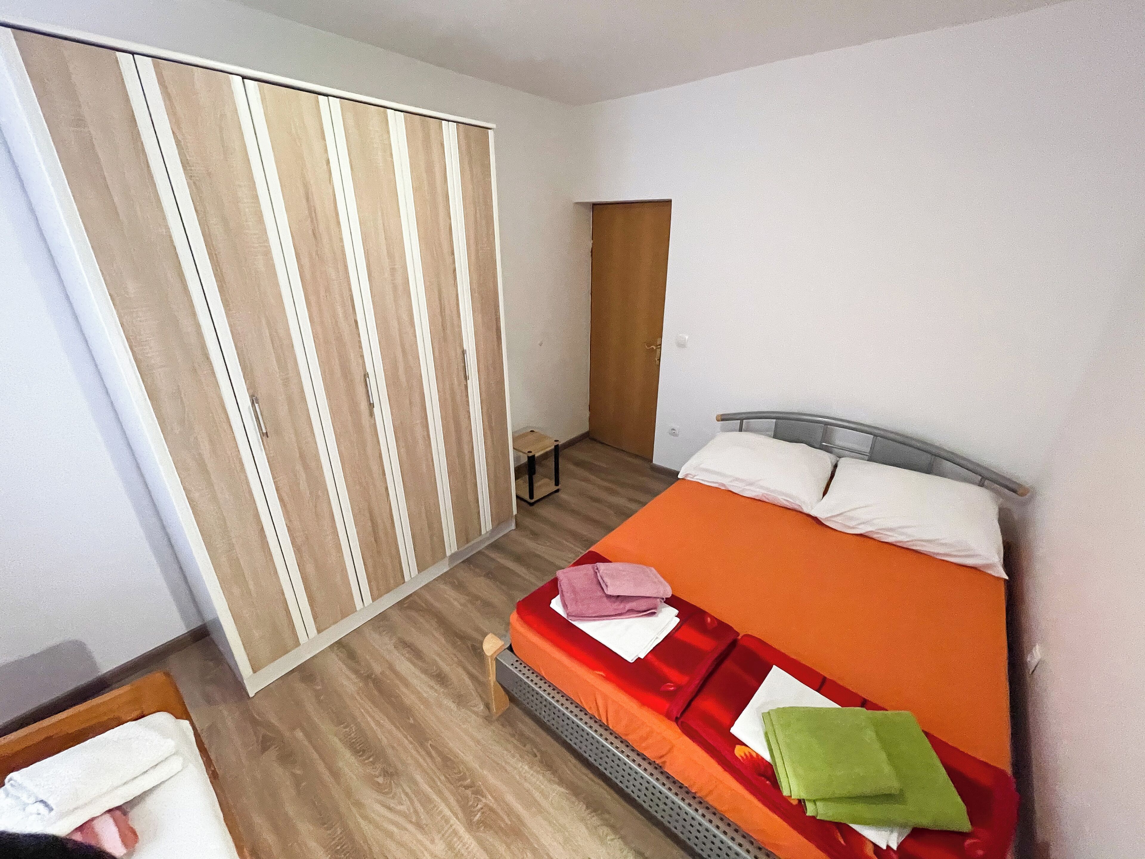 A bedroom with a bed, a wardrobe, and a small table.