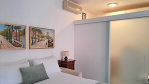 A bedroom with a bed, pillows, a nightstand with a lamp, and two framed paintings on the wall. - Casa Romana  (Sanremo)