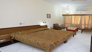 Une chambre d’hôtel avec un grand lit, deux fauteuils, une petite table et un téléviseur.