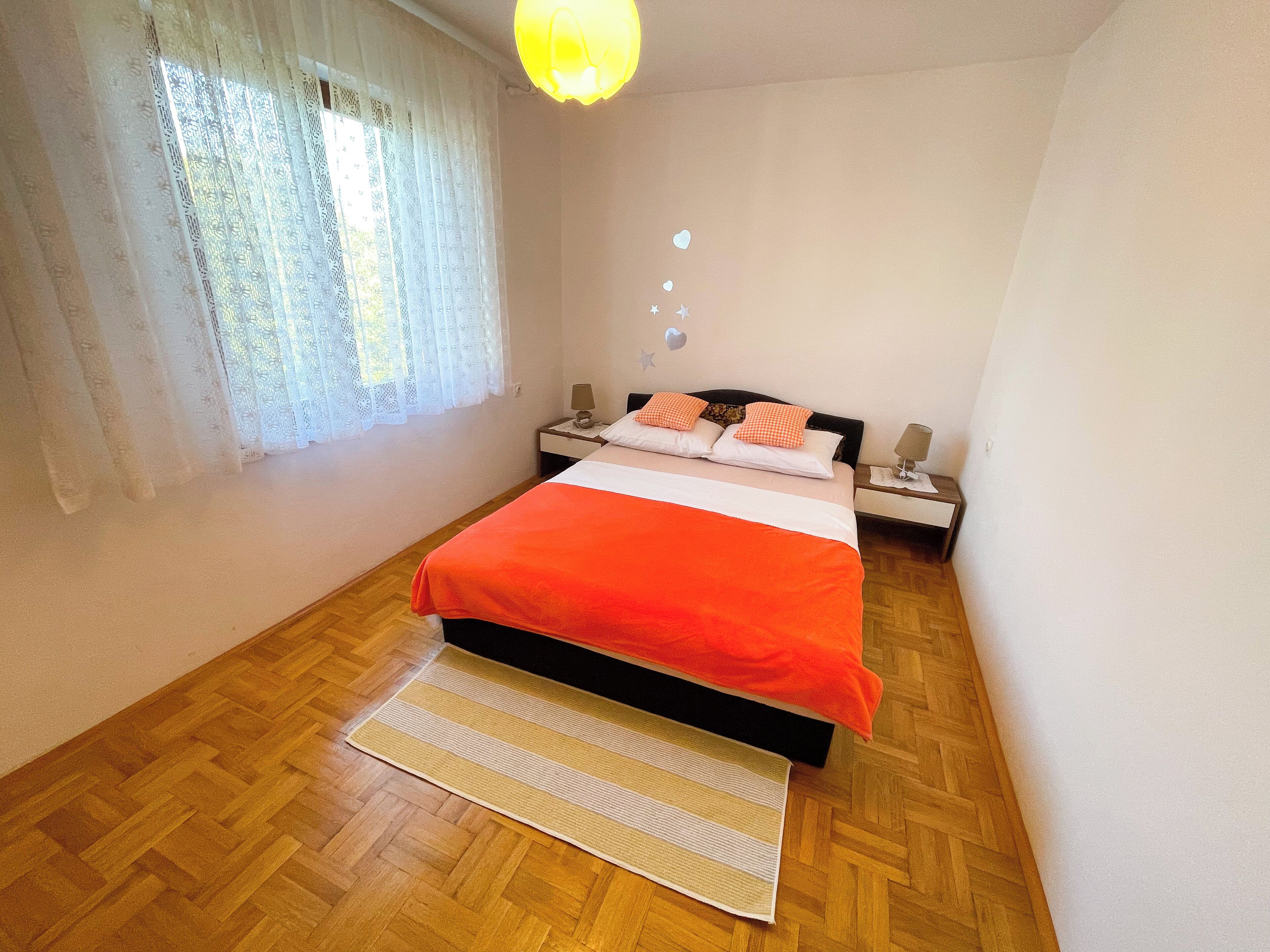 Une chambre à coucher avec un lit, des tables de chevet, une lampe et une fenêtre avec des rideaux.