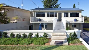 Ein zweistöckiges Haus mit Balkon, einer Treppe und einem gepflegten Garten.