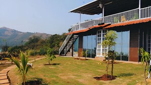 A modern building with a balcony, a staircase, and a well-maintained lawn with young trees. - Forrest Homestay Villa (Bhor)