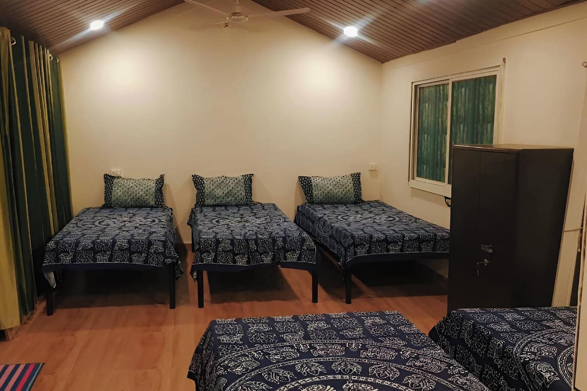 A room with three beds, a window, and a wardrobe.