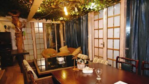 A traditional Japanese-style room with tatami mats, a low wooden table, and a sofa with cushions. - Forrest Homestay Villa (Bhor)