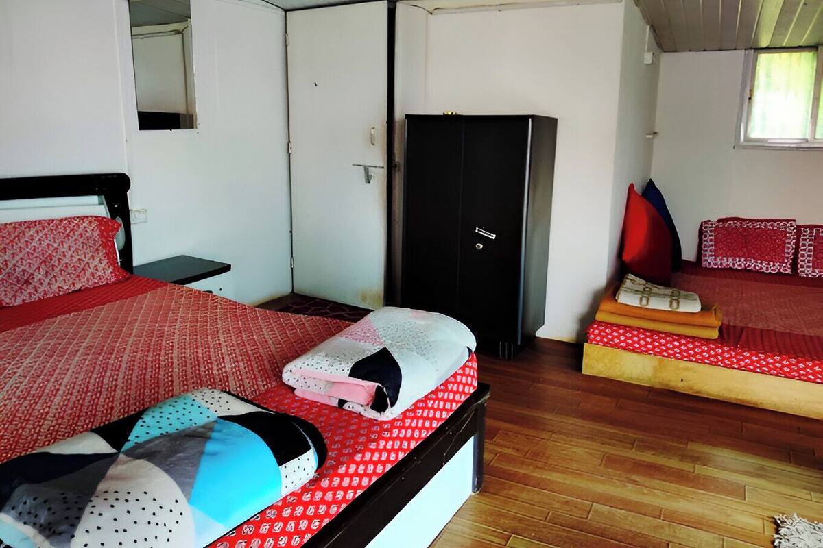 A room with two beds, a wardrobe, and a small table.