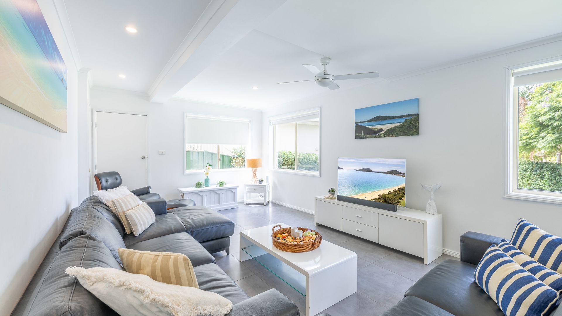 A modern living room with a grey sofa, white coffee table, and a television.