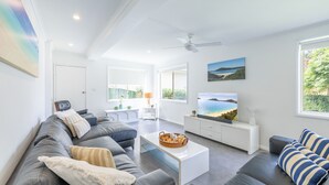 A modern living room with a grey sofa, white coffee table, and a television.