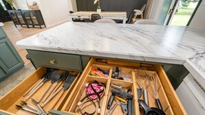Eine Küche mit Marmorarbeitsplatte und einer Schubladenleiste, die verschiedene Küchenutensilien enthält.