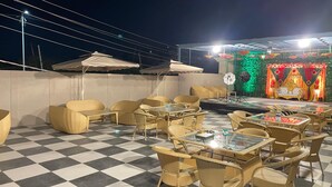 An outdoor seating area with wicker furniture and checkered flooring. - The Royal Inn (Faridabad)