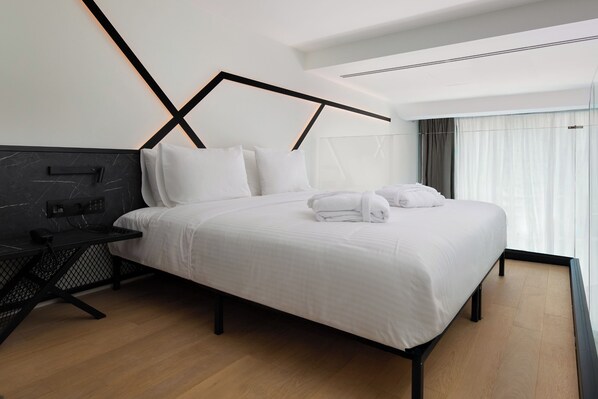 Habitación de hotel moderna con una cama grande, un escritorio y vistas a la ciudad.