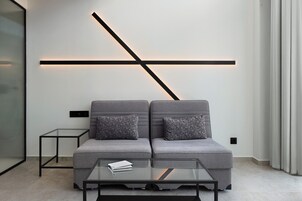 Una sala de estar moderna con un conjunto de sofás, una mesa de centro de vidrio y un diseño de pared minimalista con iluminación.