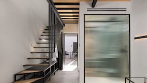 Un intérieur moderne avec un escalier, une cloison en verre et un espace salon.