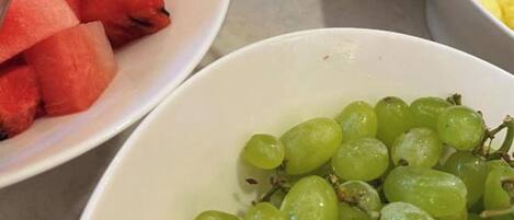 Una mesa con tazones de sandía, uvas y trozos de piña.