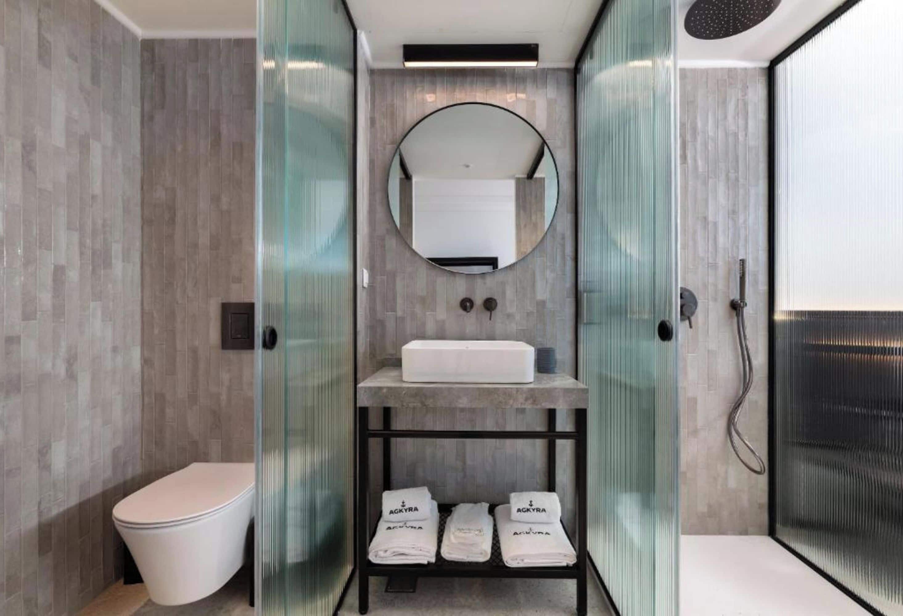 A modern bathroom with a toilet, a sink on a shelf, and a shower area.