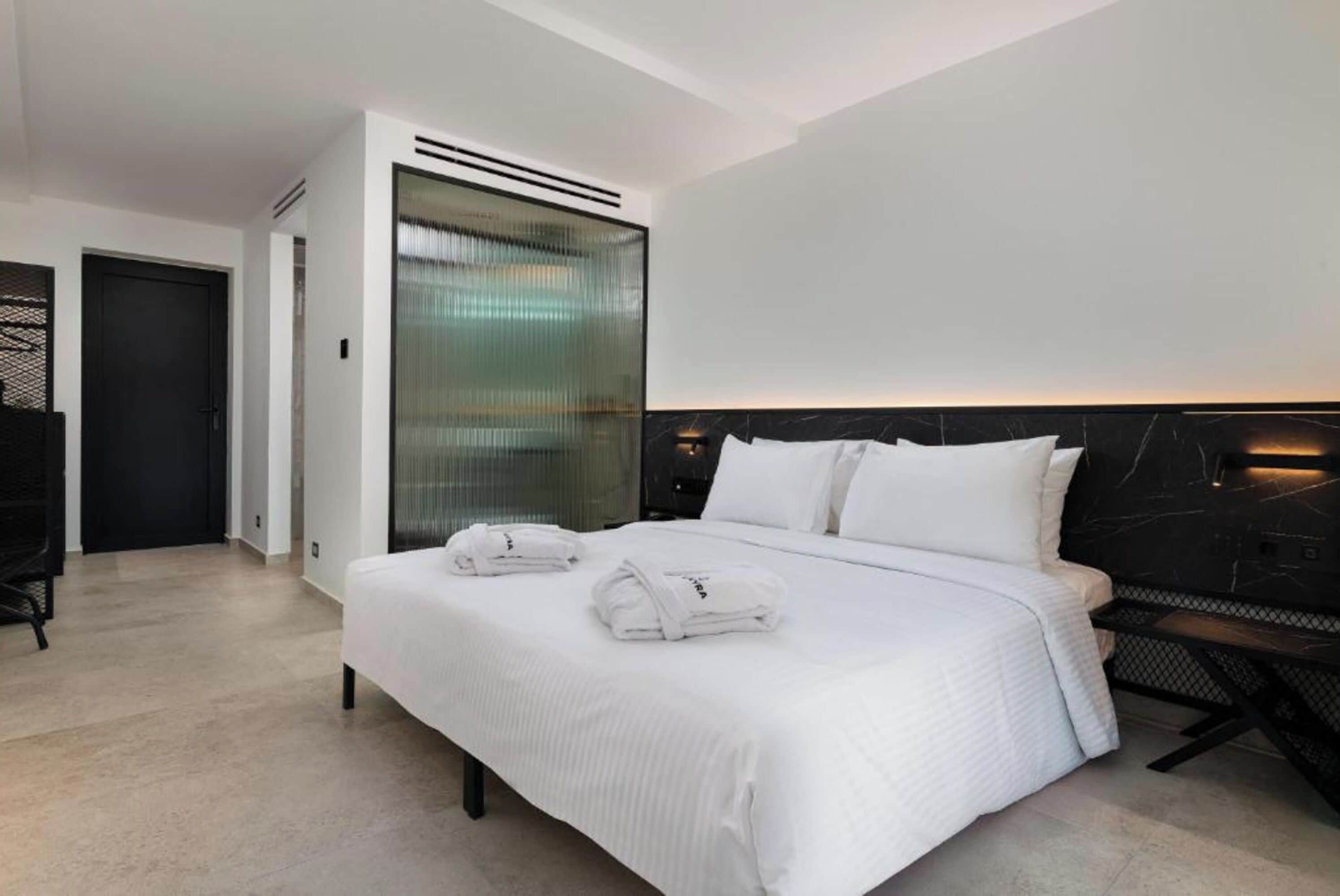Une chambre d’hôtel moderne dotée d’un grand lit, d’un bureau et d’une cloison en verre.