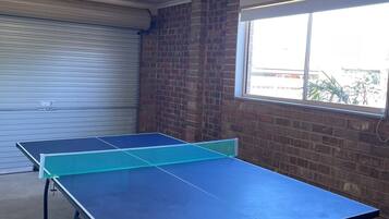 A ping pong table in a room with a brick wall and a window.