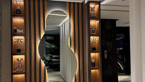 A modern interior with a unique wall design, a visible staircase, and a bathroom with a sink and toilet. - ELYSIAN HOTEL  (Abuja)