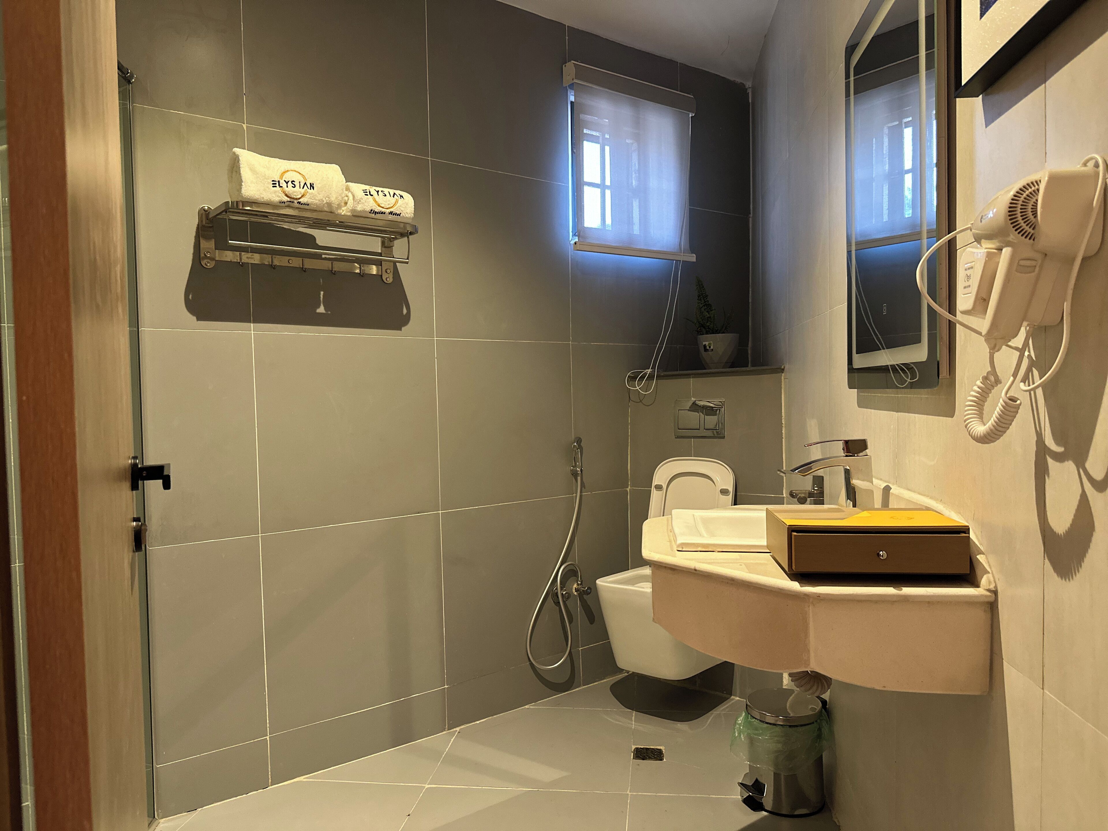 A modern bathroom with a glass shower enclosure, a toilet, a sink with a mirror, and a hairdryer on the wall.