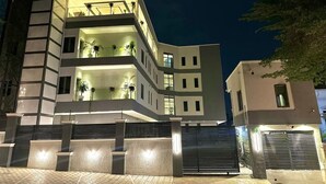 A modern multi-story building with balconies, a gated entrance, and a well-lit facade. - ELYSIAN HOTEL  (Abuja)