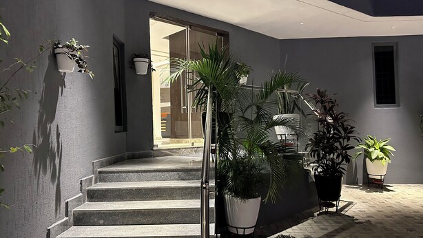 A staircase leading to a door, surrounded by potted plants and a tiled floor. - ELYSIAN HOTEL  (Abuja)