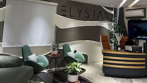 A modern reception area with a large whiteboard, a reception desk, and seating arrangements including a sofa and chairs. - ELYSIAN HOTEL  (Abuja)