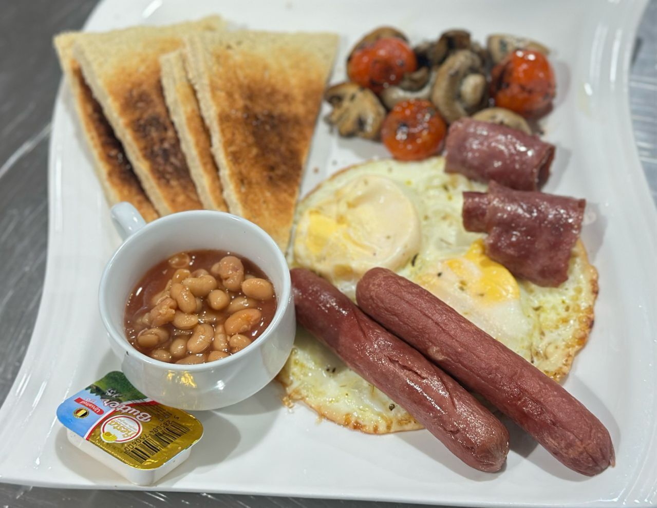 Un plato con tostadas, huevos, salchichas, frijoles y champiñones.