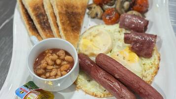 Un plato con tostadas, huevos, salchichas, frijoles y champiñones.
