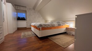 A bedroom with a bed, bedside table, and a window. - Cozy vacation apartment in an idyllic natural location (Rosenthal-Bielatal)