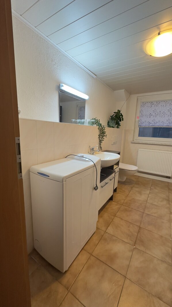 A compact kitchen with a built-in washing machine, a sink, and a window with a view.