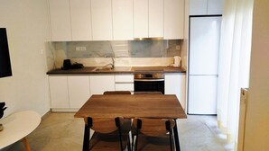 A compact kitchen with white cabinets, a marble backsplash, and a built-in oven.