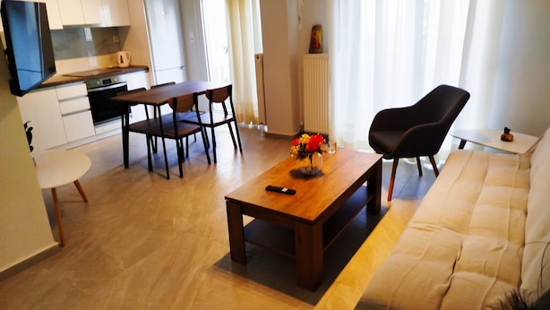 A modern living room with a sofa, a coffee table, and a dining area with chairs and a table.