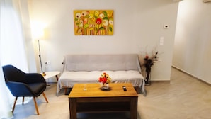 A living room with a sofa, a coffee table with a vase of flowers, a black chair, and a painting on the wall.