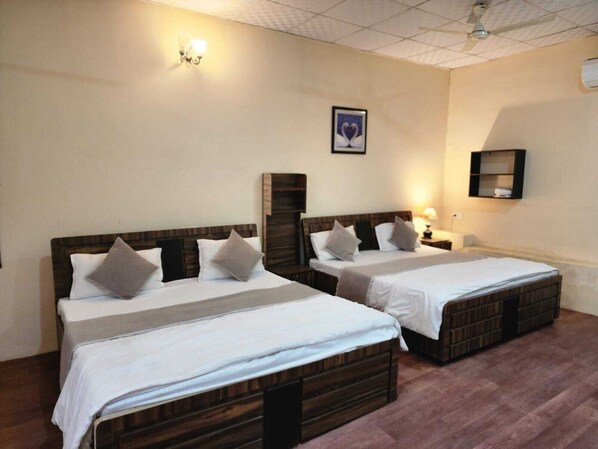 A room with two wooden beds, white bedding, a wall-mounted shelf, and a ceiling fan. - Altara Resort (Jaipur)